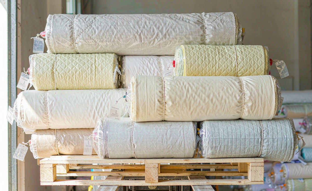 GorgeousBen fabric lead time - woven fabric rolls with mill tags in a garment factory store